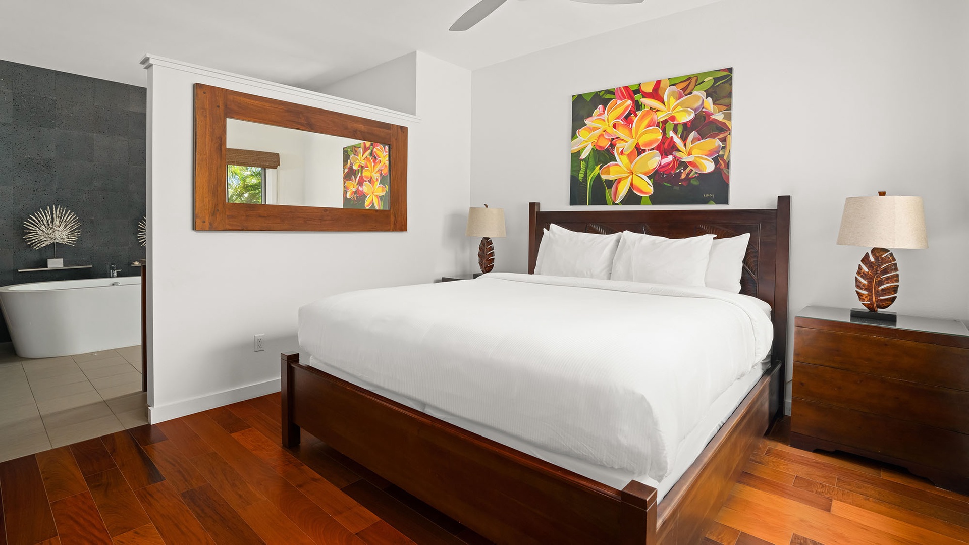 Drift off in your tranquil bedroom with crisp white linens, tropical artwork, and warm wooden furnishings. The attached spa-style bath awaits your morning refresh.