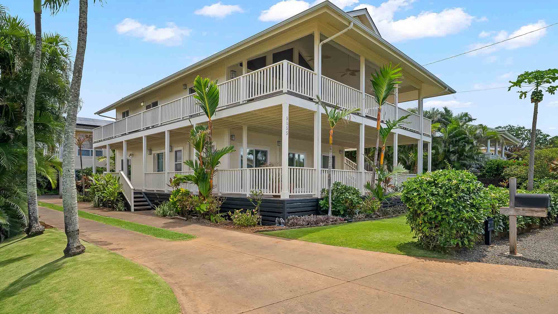 A charming two-story tropical property with wraparound balconies, surrounded by lush palms and manicured lawns, offering a serene island retreat with classic coastal architecture.