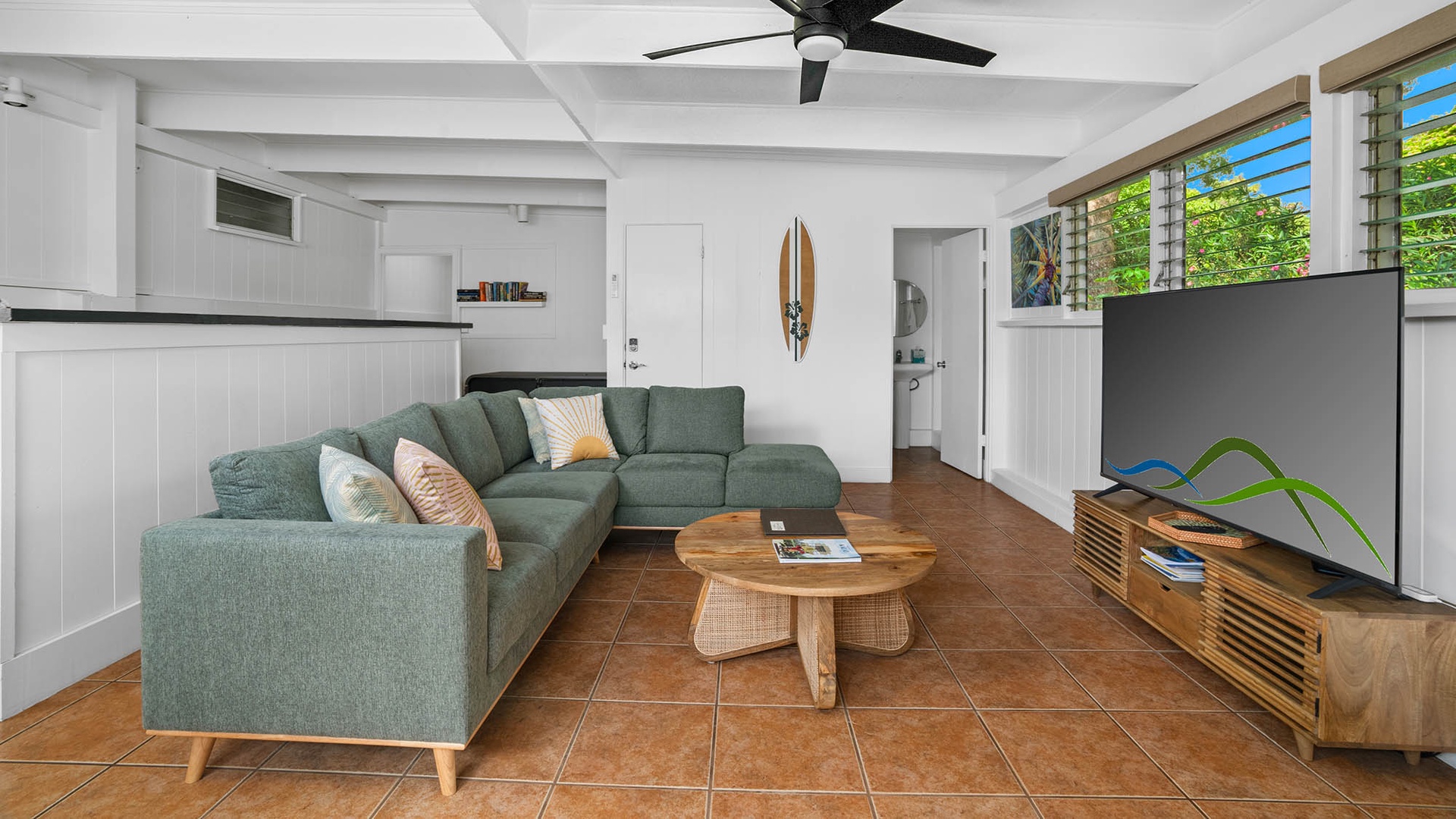 Unwind in your bright, coastal-inspired living room where a comfy sectional invites you to relax after a day of adventure. Natural light and a gentle ceiling fan keep things breezy.