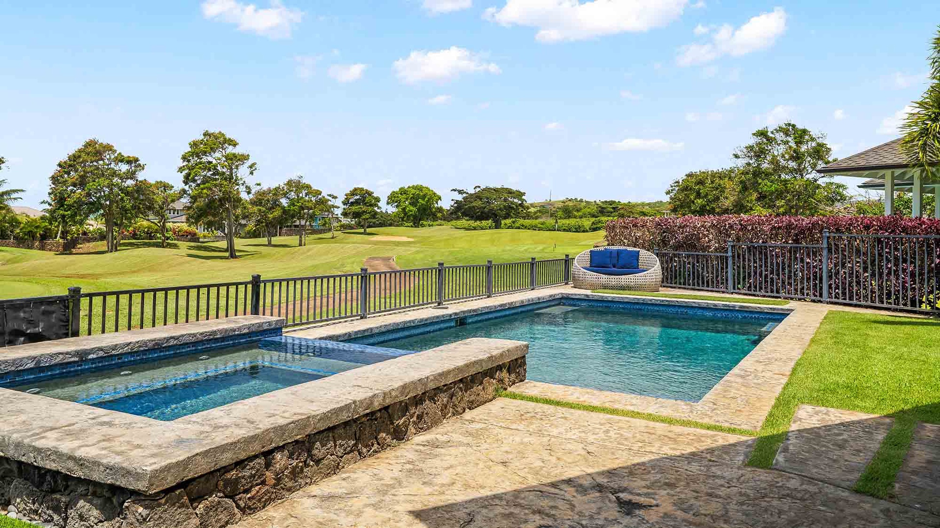 The property features a private pool and hot tub overlooking a scenic golf course, offering a peaceful setting with lush landscaping and open skies.