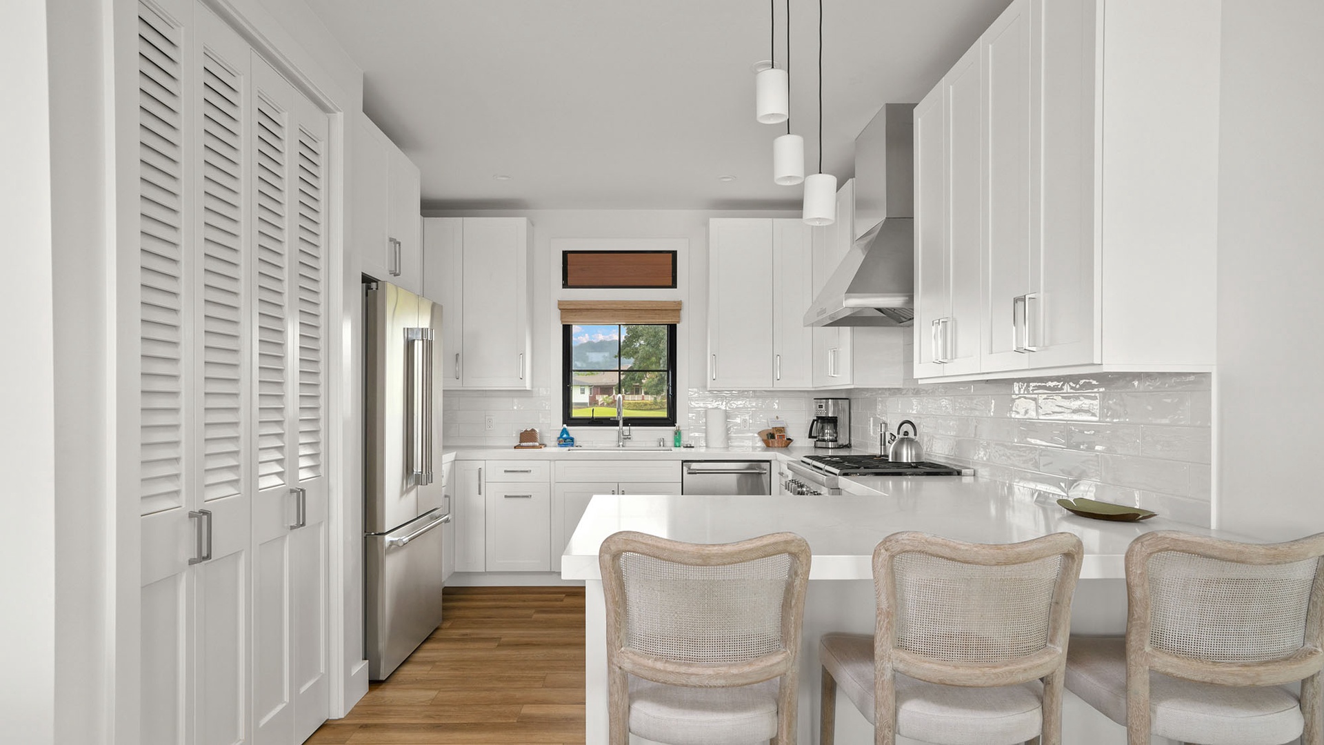 Your sleek white kitchen awaits with modern appliances and elegant pendant lighting for memorable meal preparation.