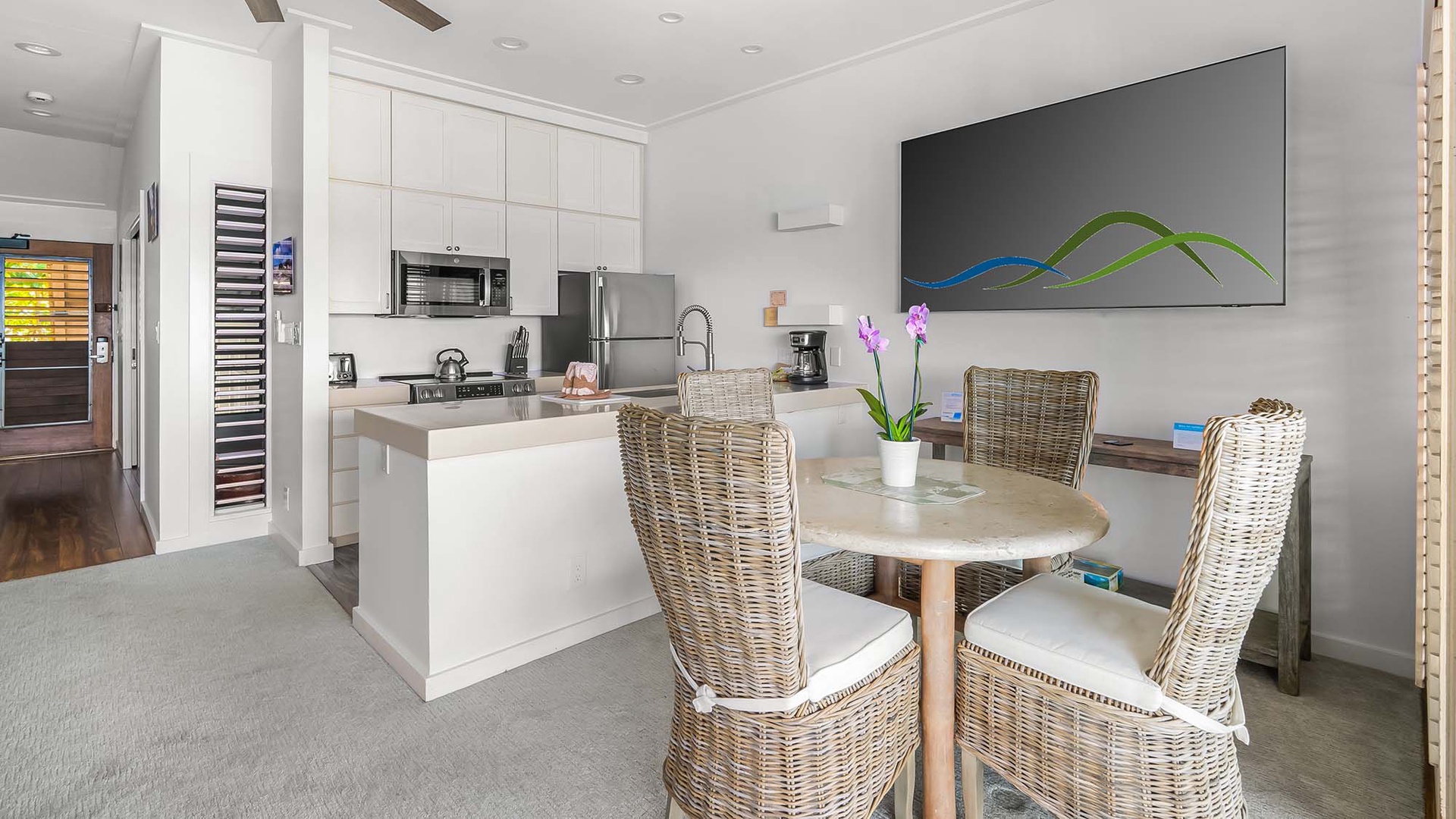 Picture yourself preparing meals in this sleek, modern kitchen, complete with stainless steel appliances and ample counter space. Dine at the cozy table for four, surrounded by coastal-inspired wicker chairs and natural light.