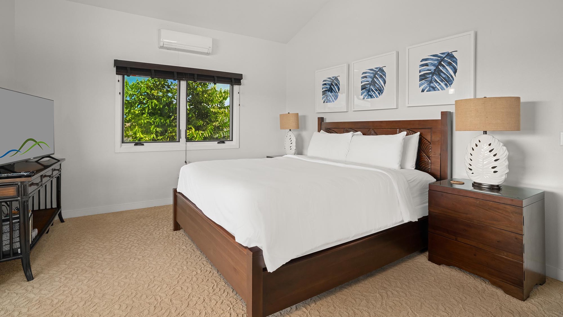 Your serene bedroom retreat features a plush bed, tropical artwork, and lush garden views framed by your window—perfect for restful mornings and peaceful nights.