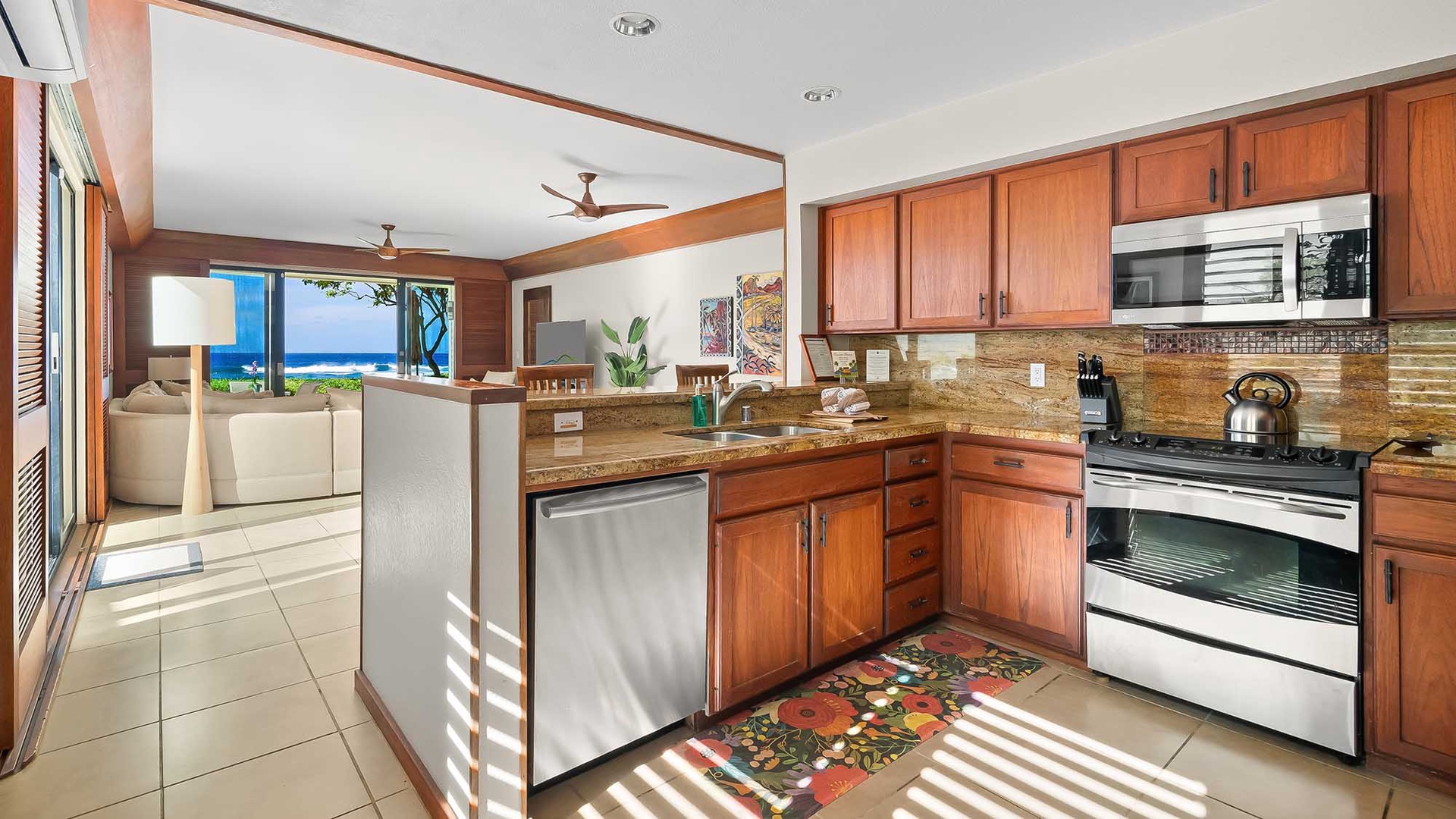 Your fully-equipped kitchen awaits, featuring rich wood cabinetry and sparkling granite counters, all framed by natural light and ocean views beyond.
