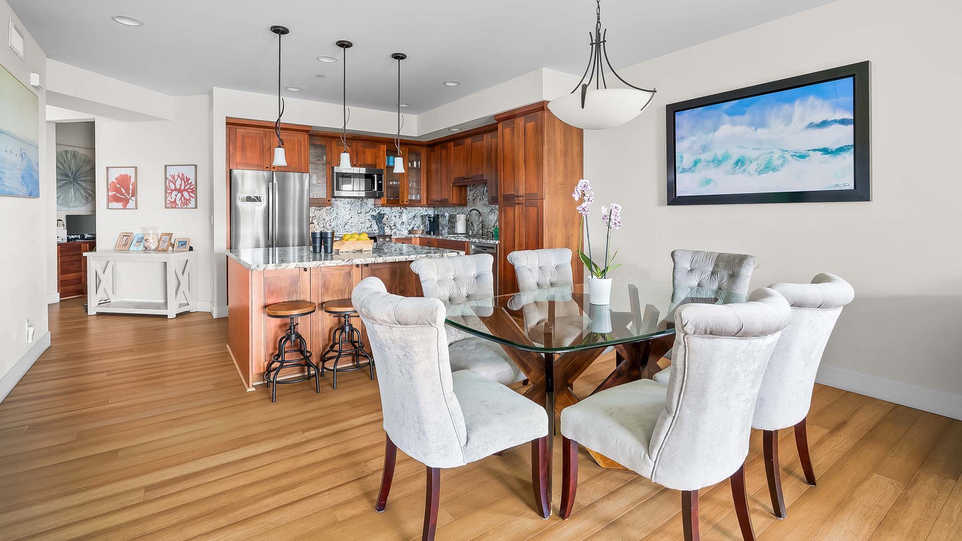 Gather around the elegant glass dining table for meals together, with a fully equipped kitchen just steps away ready for your culinary adventures.
