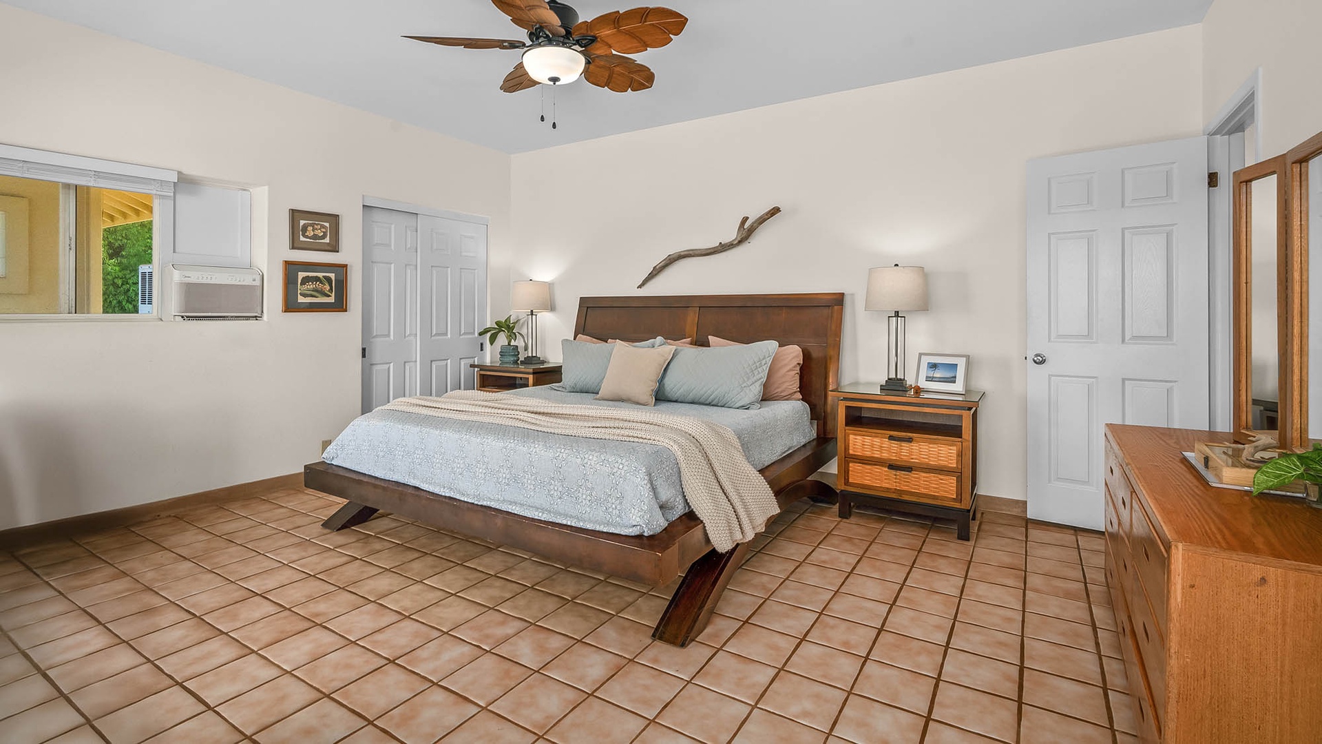 Slip into your comfortable island retreat with tropical ceiling fan, warm wood furnishings, and tile floors that stay cool underfoot. This serene bedroom invites you to unwind after a day of adventure.