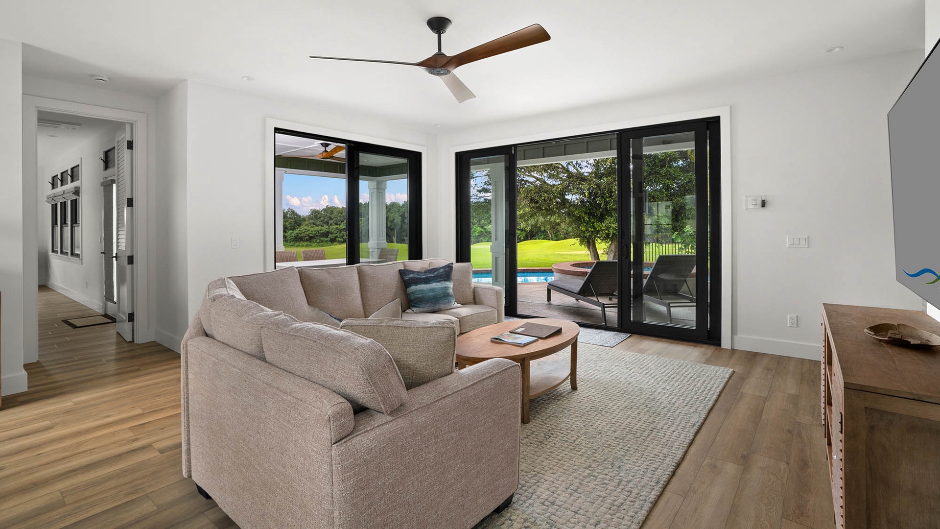 Relax in your bright living room where floor-to-ceiling windows frame peaceful garden views and a ceiling fan keeps you cool.