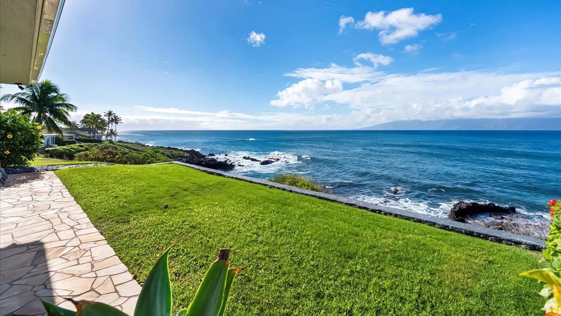 Oceanfront property features expansive lawn overlooking dramatic coastline with rocky shores and endless Pacific views.