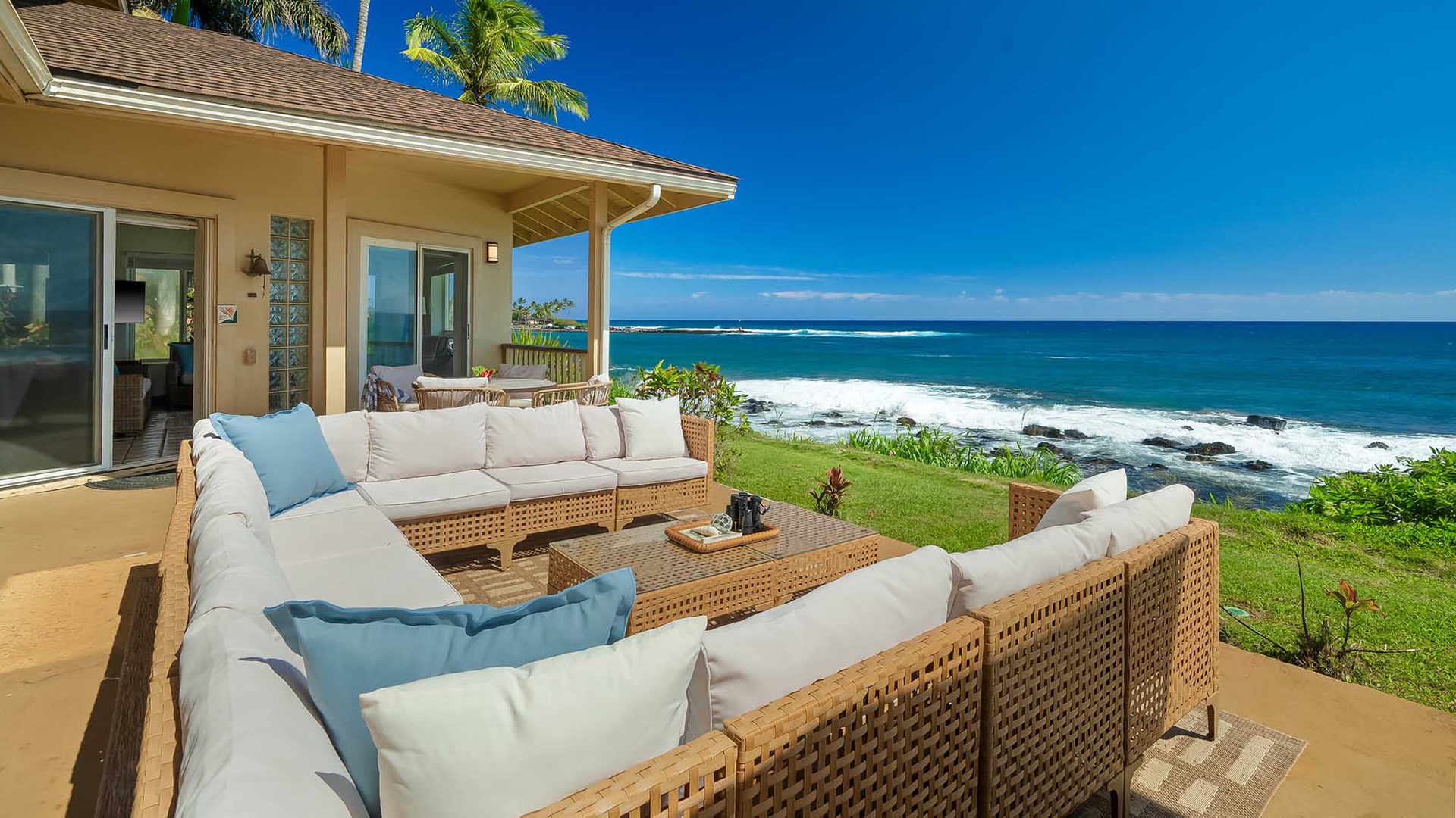 Stunning oceanfront property with direct access to lush green lawn, breathtaking Pacific waves, and swaying palms—a coastal haven framed by endless blue skies.