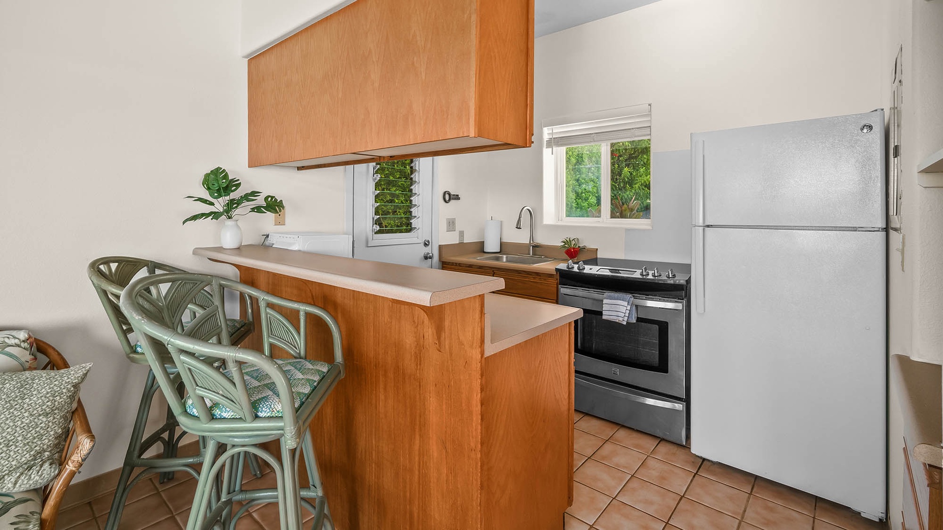 Your fully equipped kitchen lets you whip up meals with ease, featuring a stylish breakfast bar for cozy mornings and a splash of tropical greenery adding warmth to the space.