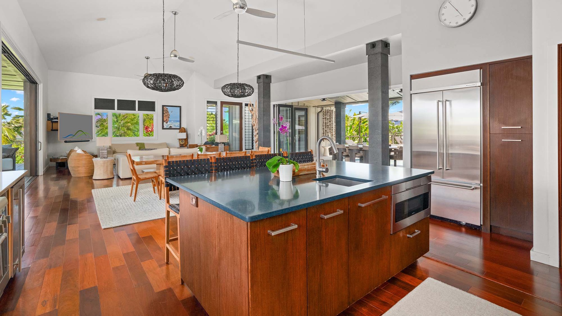 Gather in your open-concept retreat where a sleek kitchen island flows into the dining and living spaces, framed by tropical views and warm wood tones to welcome your island escape.