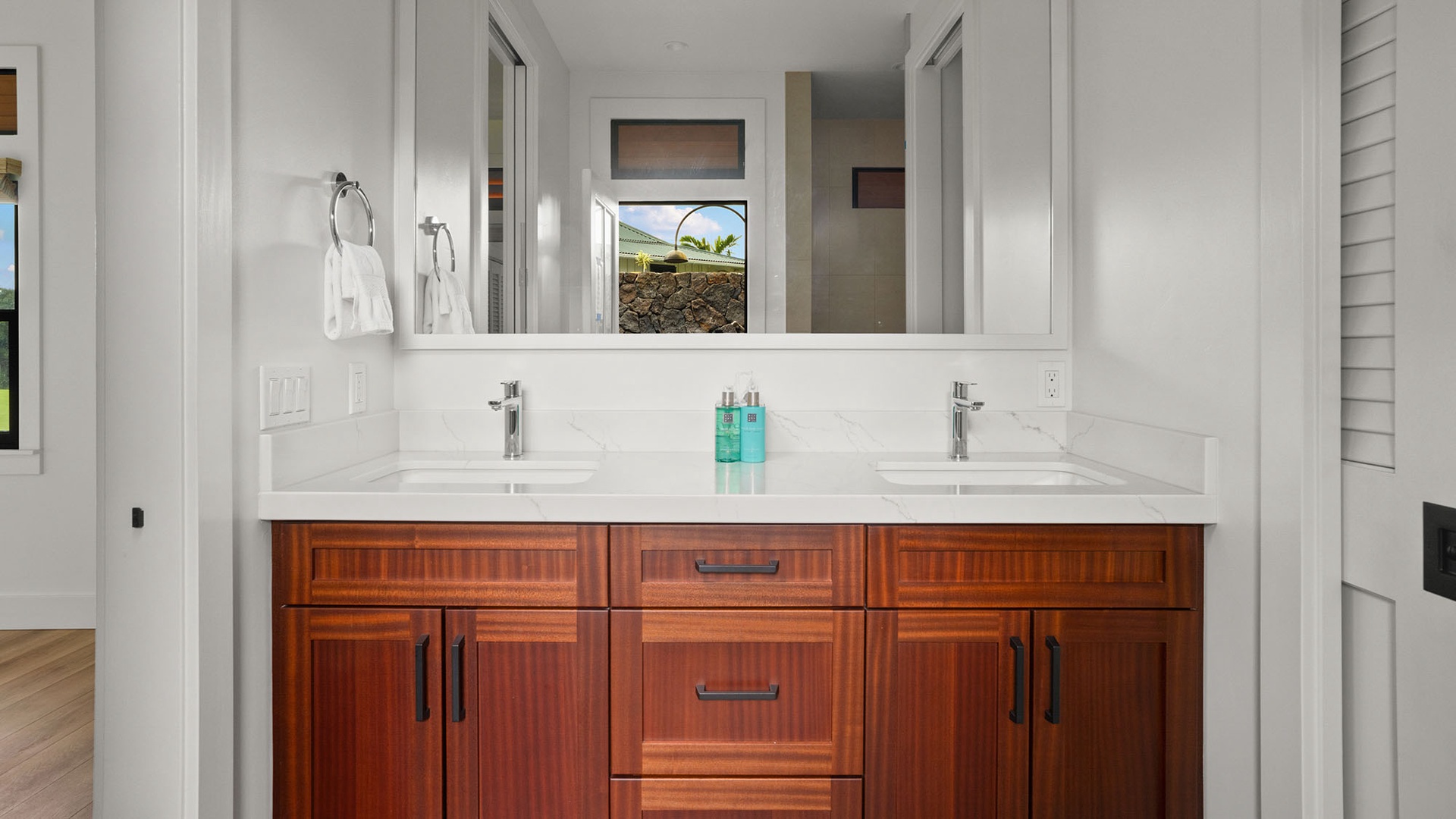 Your elegant dual-sink vanity offers plenty of space to get ready, with rich wood cabinetry and pristine white countertops.