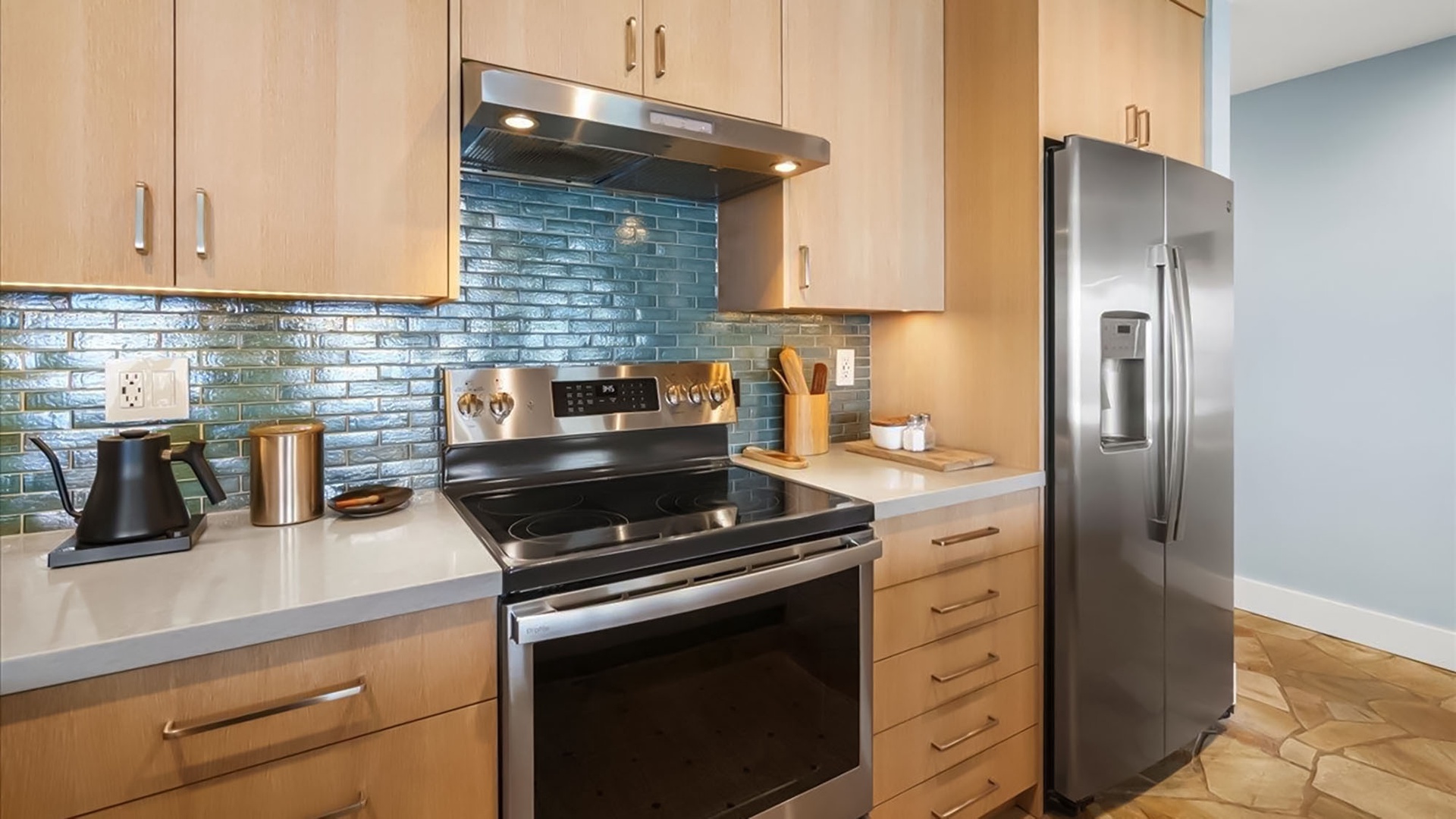 Cook your favorite meals in this stylish kitchen featuring gleaming stainless appliances, striking blue tile backsplash, and ample counter space for all your culinary adventures.