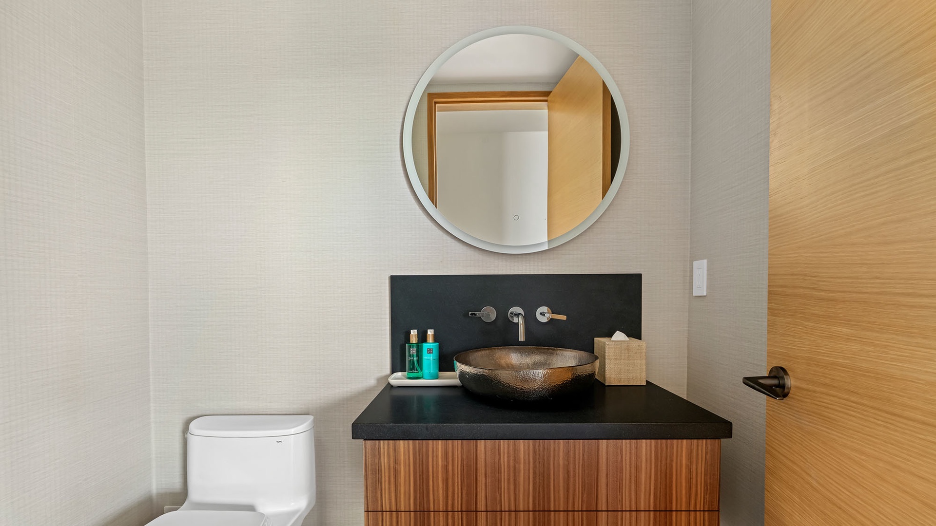 Step into your sleek, modern bathroom with a striking vessel sink, warm wood accents, and curated amenities waiting just for you.