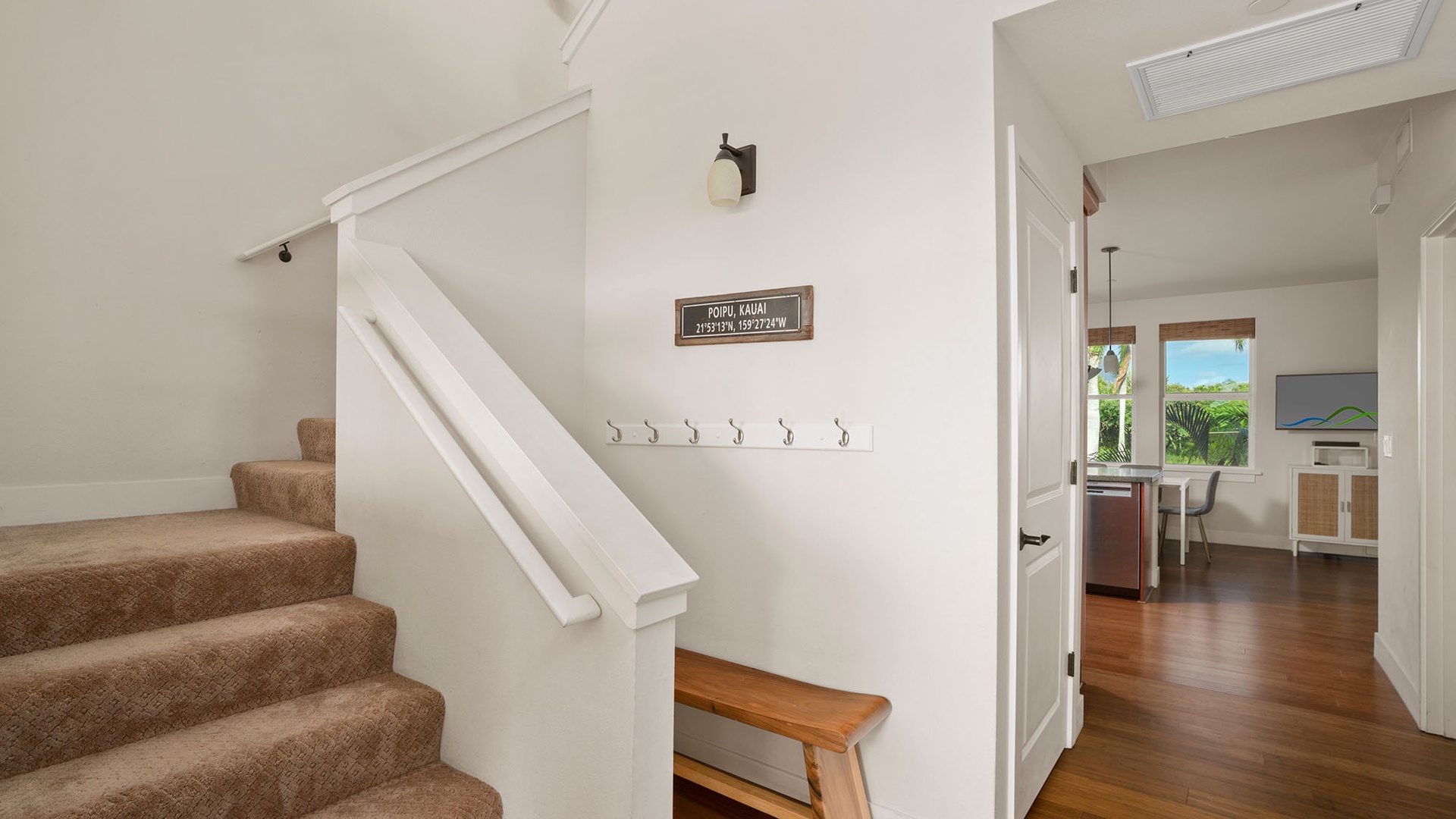 Your inviting entryway features warm wood floors, convenient hooks for your belongings, and a charming bench for settling in.