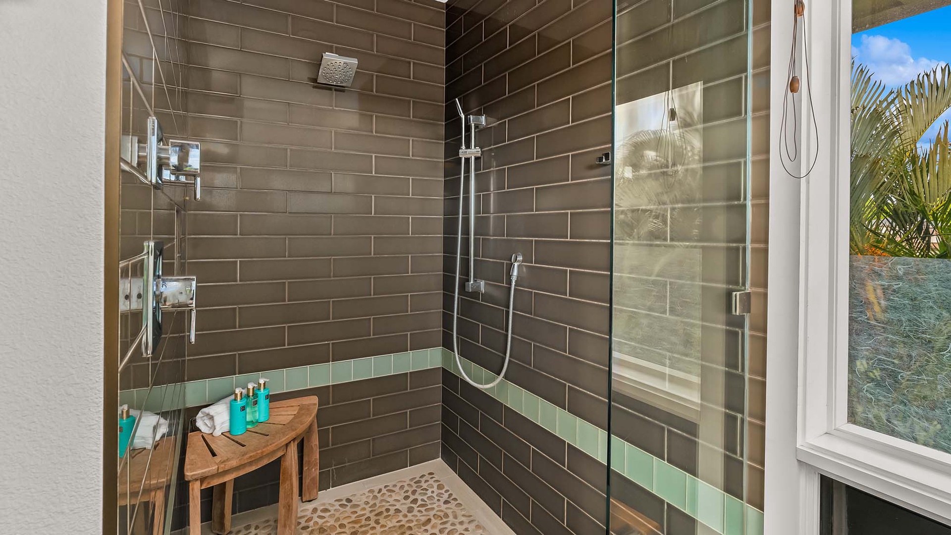 Step into your private shower oasis with sleek tiling, a rainfall showerhead, and built-in shelving for all your essentials—refreshment awaits after a day of exploring paradise.