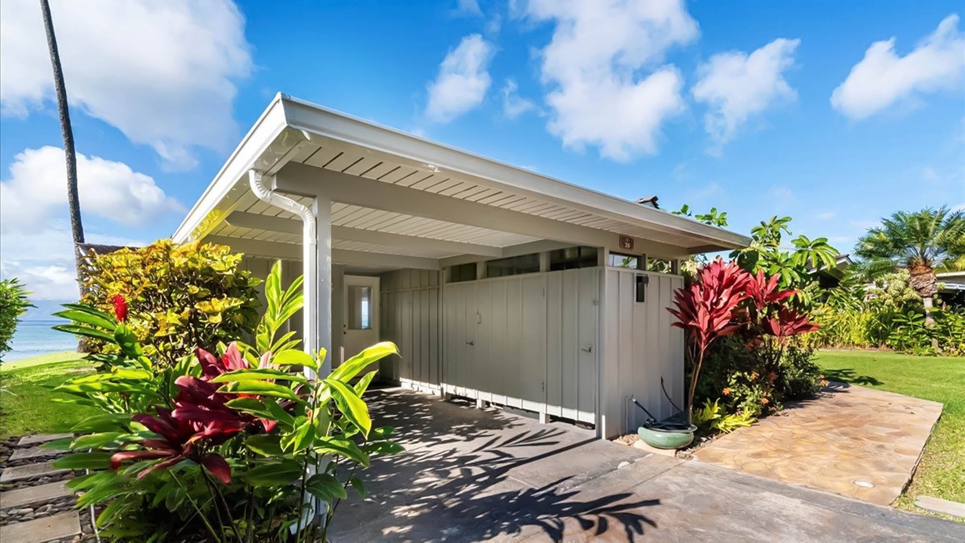 Modern beachfront retreat surrounded by vibrant tropical landscaping and manicured lawns under brilliant blue skies.