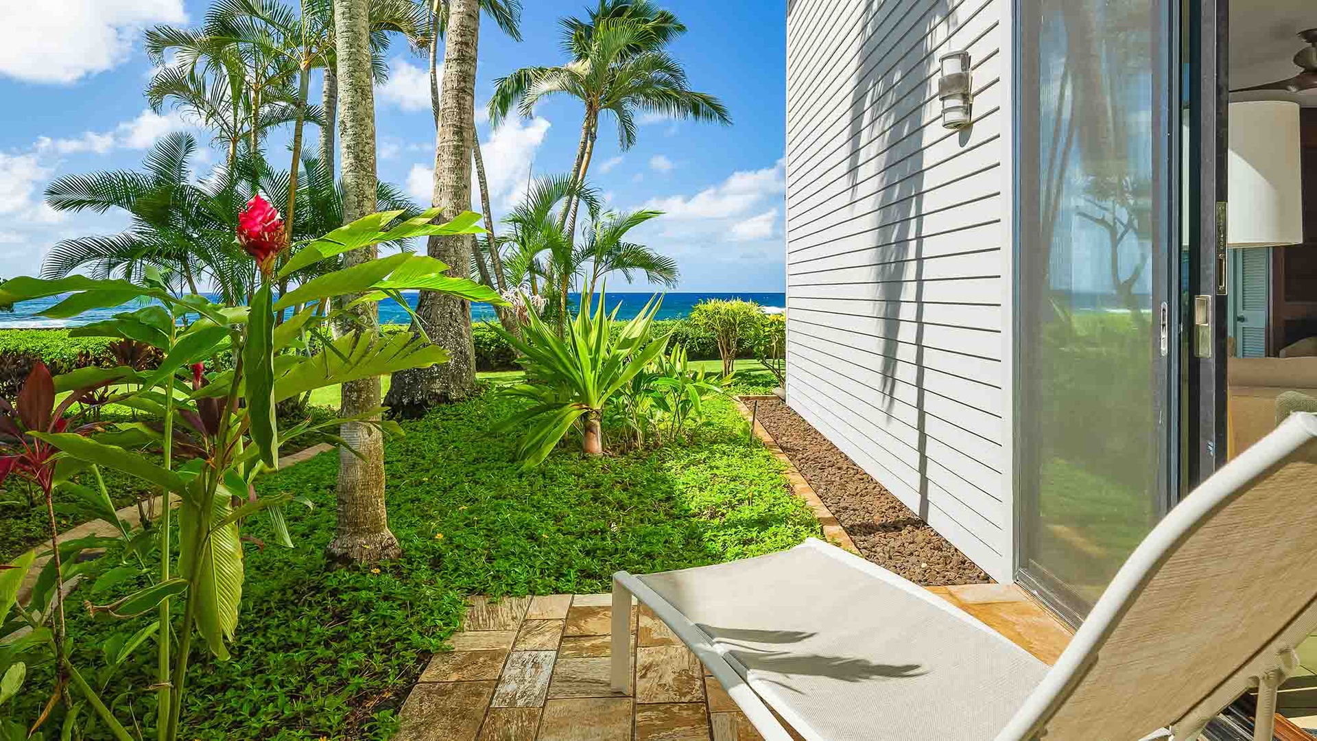 The property features a lush tropical garden setting with vibrant native palms and plantings, offering an oceanside retreat in paradise.