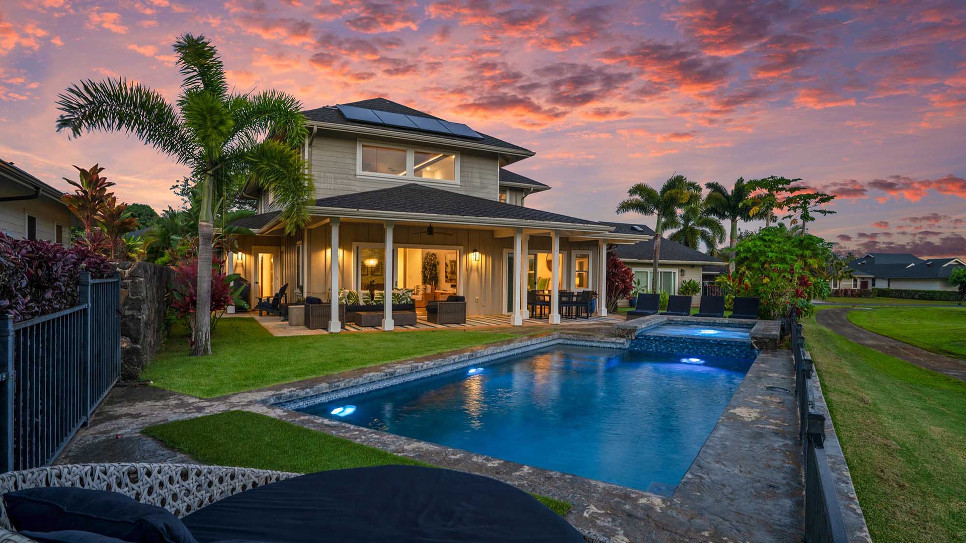 This beautiful two-story property features lush tropical landscaping and a sparkling private pool set against a vibrant sunset sky in a peaceful neighborhood.