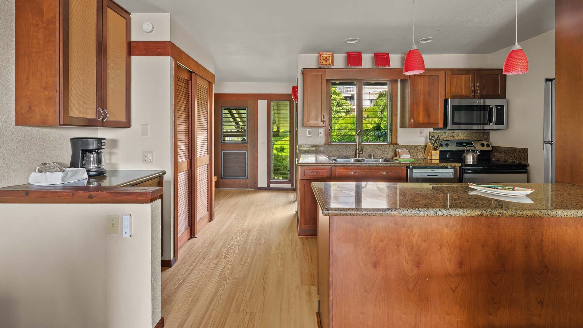 Step into your spacious open kitchen with warm wood cabinetry, granite counters, and a welcoming island perfect for prepping meals or savoring morning coffee while tropical breezes drift through the windows.