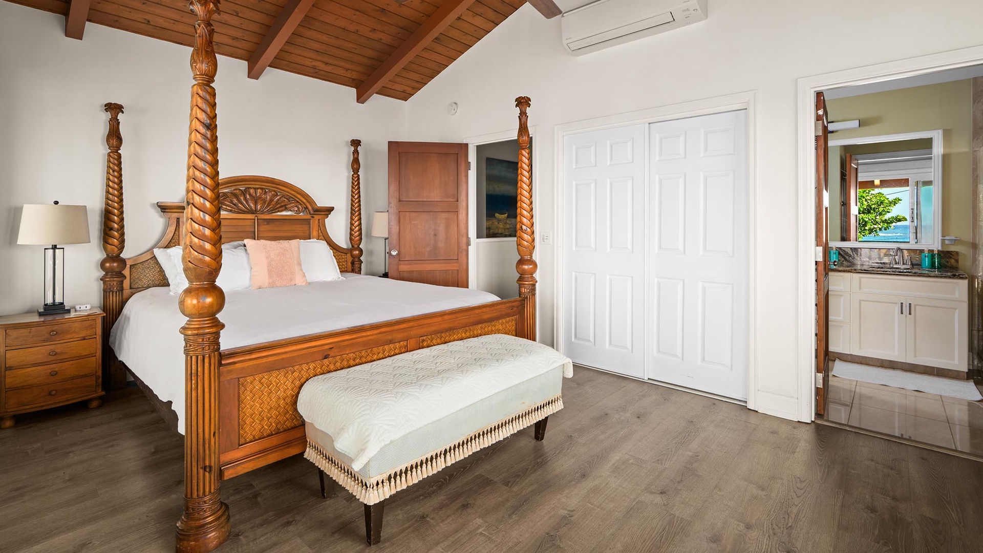 Unwind in your elegant master suite featuring a handcrafted four-poster bed and warm wood beam ceilings that create a luxurious island retreat.