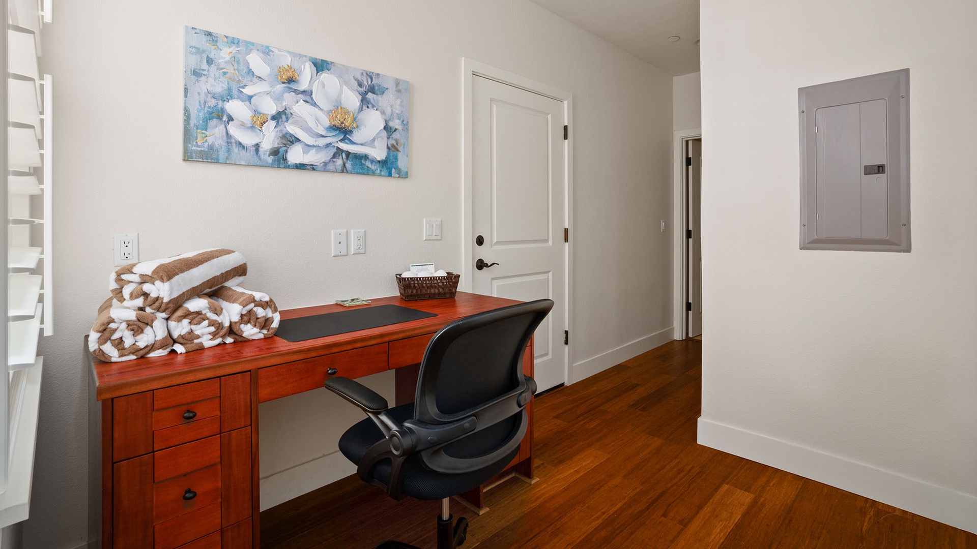 Set up your workspace at the warm wood desk, where fresh towels and bright artwork create a welcoming corner for catching up on emails or planning your day.
