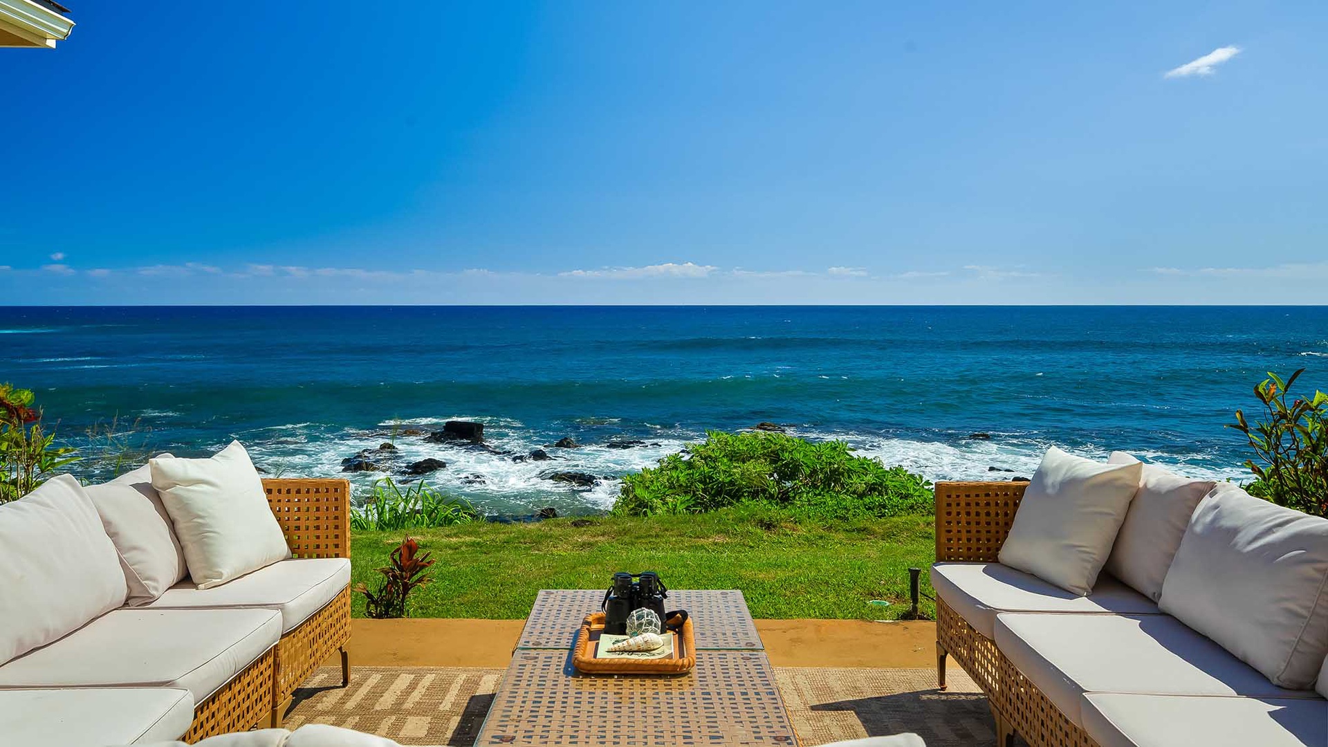 Oceanfront seating on a manicured lawn, where waves crash over rocky shores just beyond your private retreat. Settle in with morning coffee or sunset drinks, surrounded by endless blue.