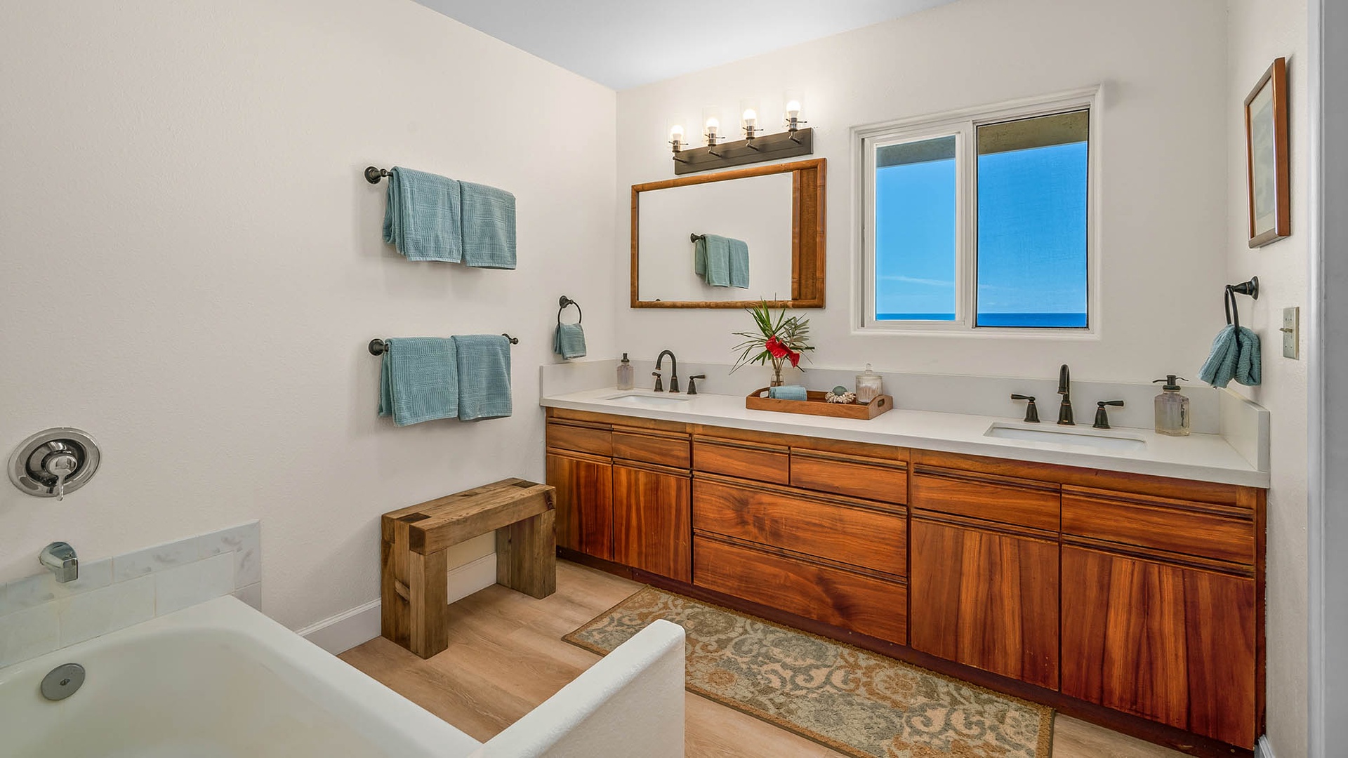 Step into your spa-like retreat with dual sinks, warm wood vanities, and ocean views through the window—perfect for unwinding after a day of adventure.