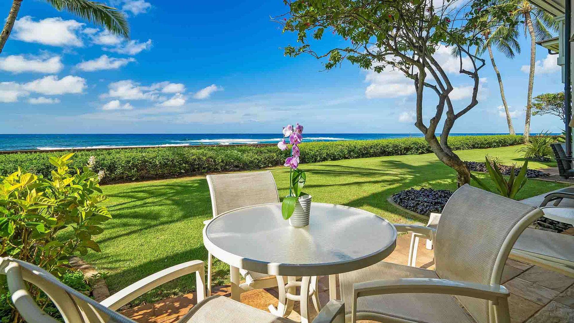 Your private lanai opens to emerald lawns and sparkling ocean views where gentle trade winds carry the scent of plumeria. Unwind here with morning coffee or sunset cocktails as waves lap the nearby shore.