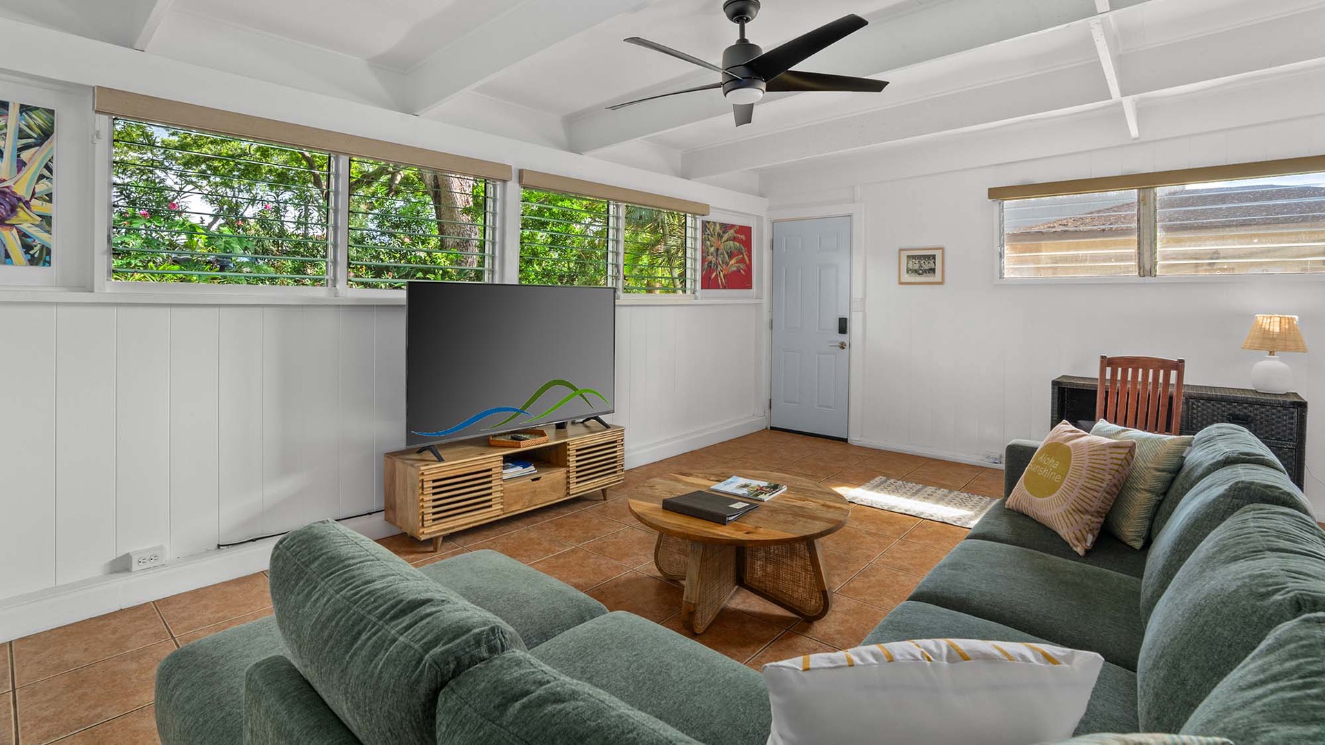 Relax in your bright living room with lush garden views streaming through the windows, plush sofas for lounging, and a ceiling fan to keep you cool on warm island days.