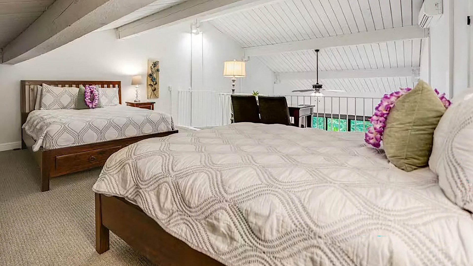 Relax in your spacious loft bedroom, featuring two comfortable beds, charming vaulted ceilings, and a cozy reading nook with a view—perfect for unwinding after a day of adventure.