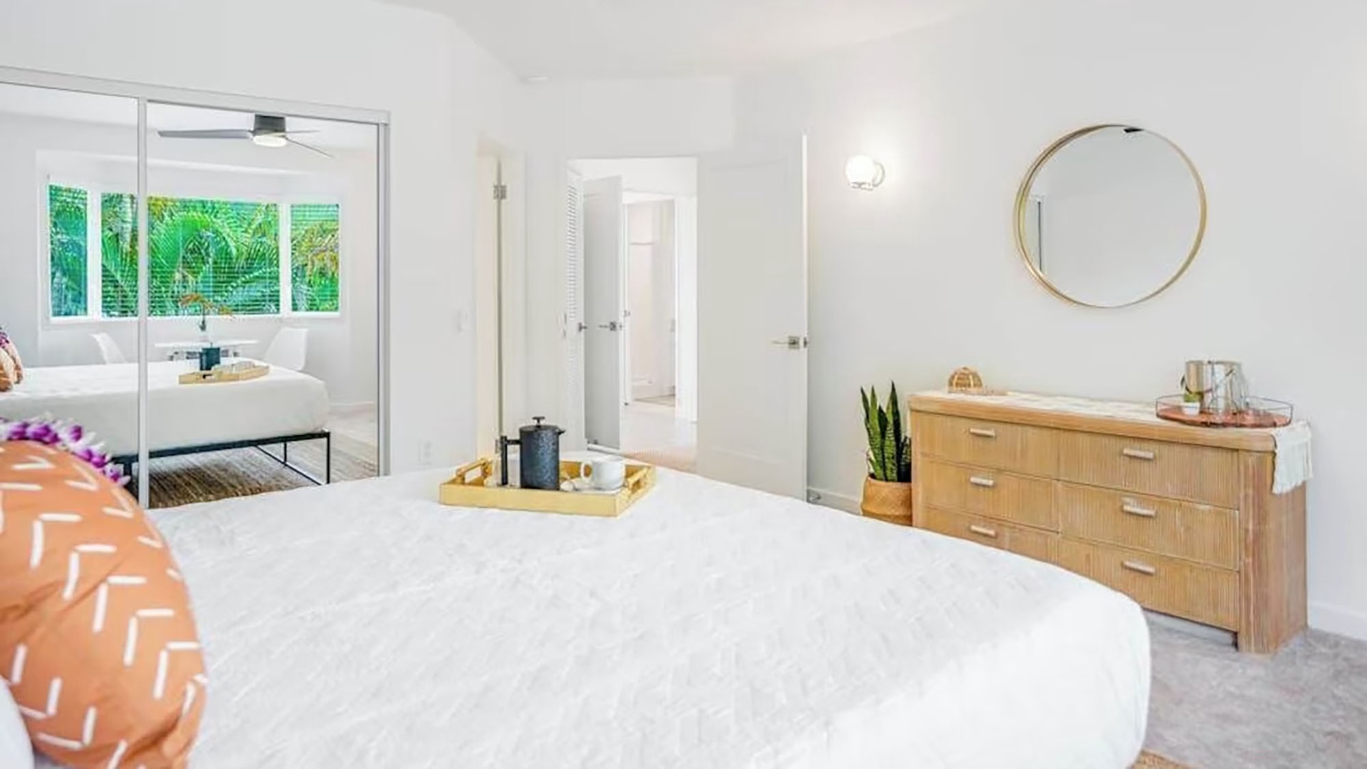 Step into your serene retreat, where crisp white linens and warm wood tones create a calming sanctuary. Through the ensuite doors, glimpse your private spa-like bathroom and lush garden views beyond.