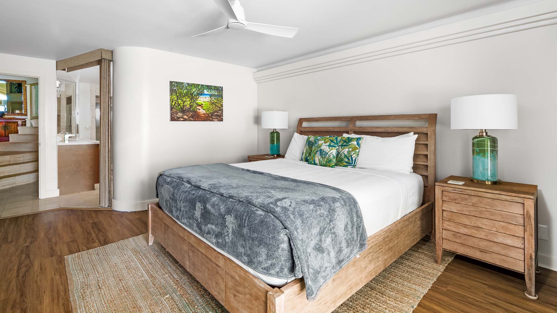 Sink into crisp linens and tropical-inspired decor in your serene bedroom retreat, complete with coastal accents and a ceiling fan for ultimate comfort.