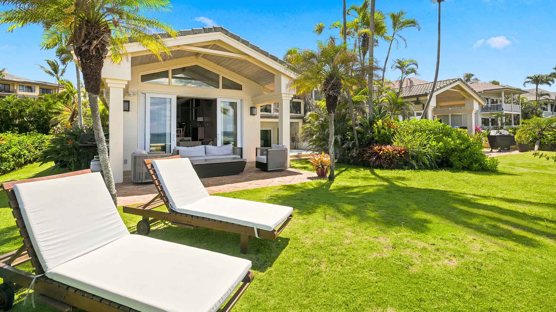 Your private tropical retreat awaits with sun-soaked loungers and lush garden leading to a bright, open living space framed by swaying palms.