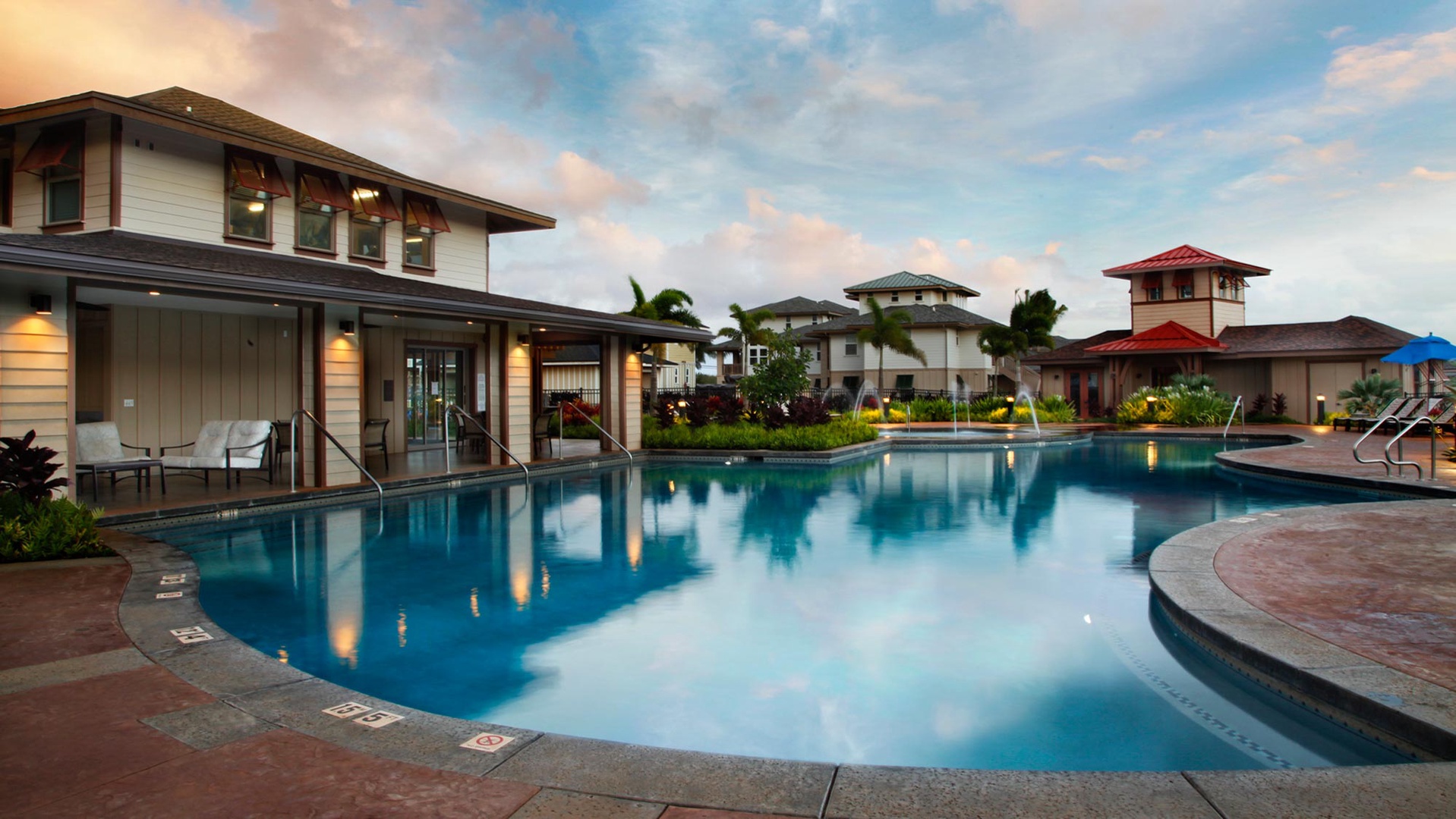 A serene resort-style pool reflects the evening sky, surrounded by tropical landscaping and modern buildings with warm lighting that creates an inviting ambiance as daylight fades.