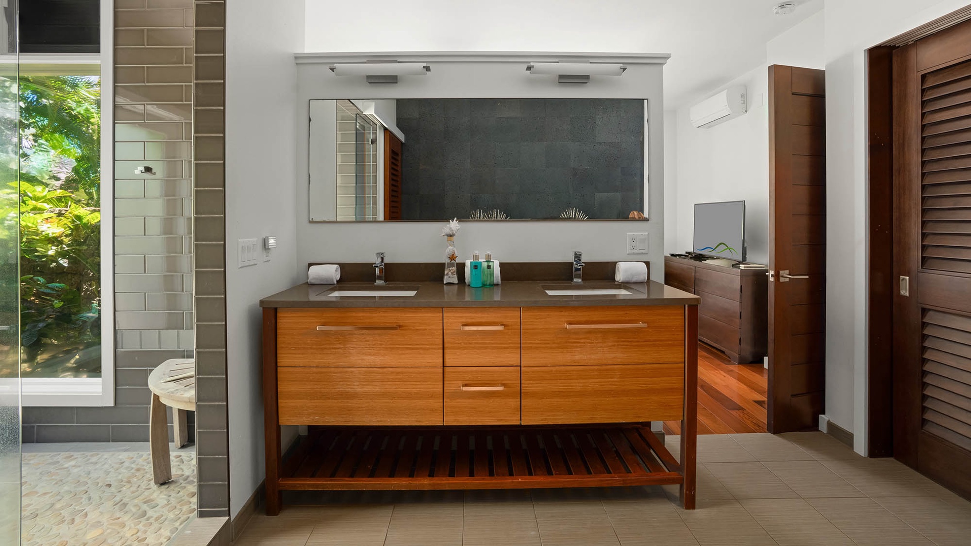 Your private bathroom features dual sinks with sleek modern fixtures, warm wood cabinetry, and a spacious layout that makes morning routines feel effortless and luxurious.