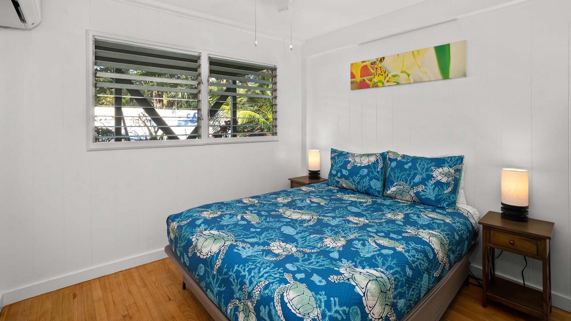 Drift off peacefully in your bright bedroom with tropical blue linens and warm wooden floors that invite relaxation.