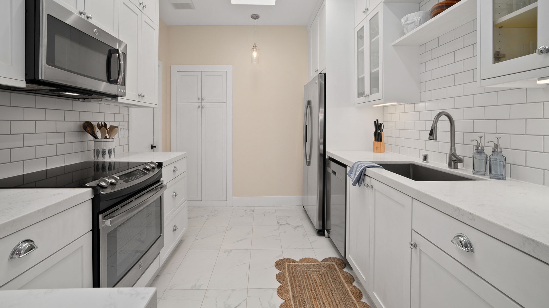 Your bright, fully-equipped kitchen features gleaming white cabinetry, stainless steel appliances, and crisp subway tile backsplash. Marble-look countertops and a farmhouse sink add a touch of elegance to your cooking space.