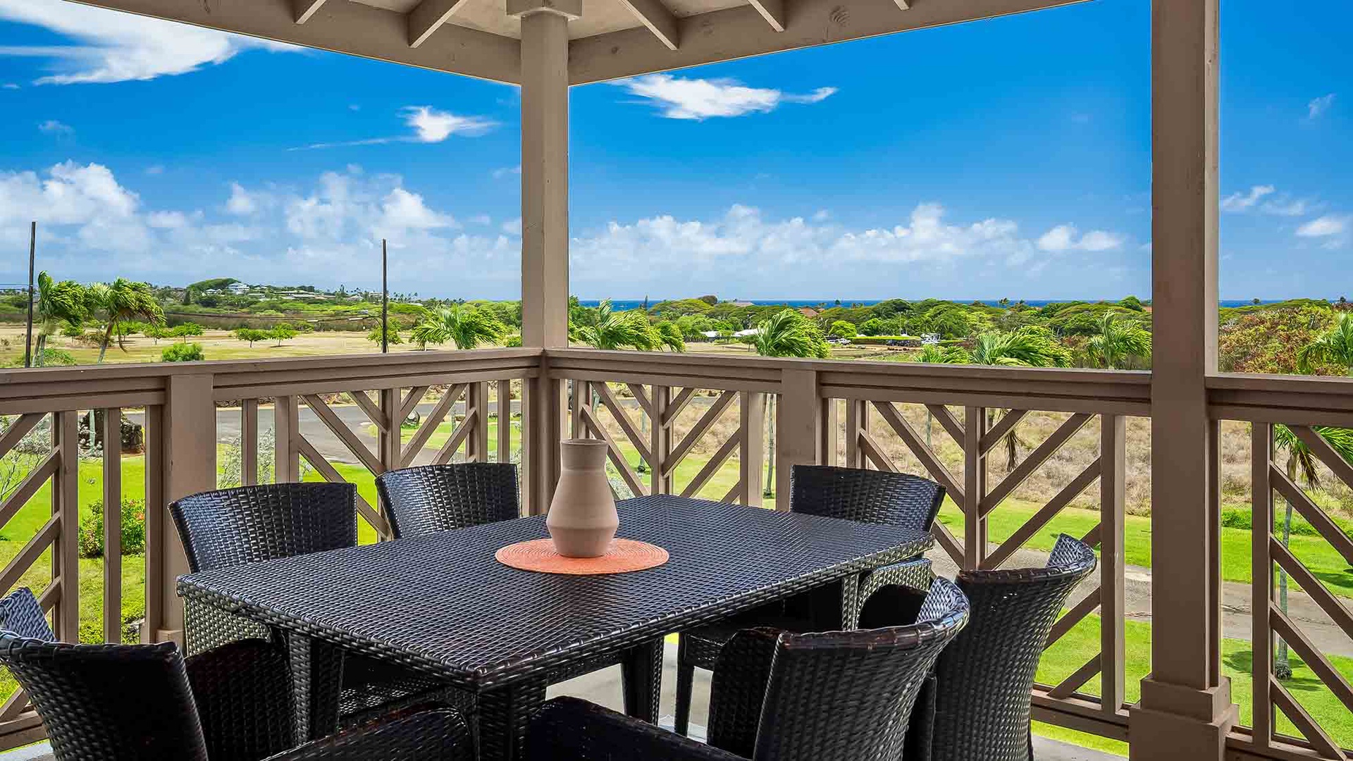 Your private covered terrace overlooks lush tropical greenery and distant ocean blues, with comfortable seating perfect for morning coffee or sunset cocktails.
