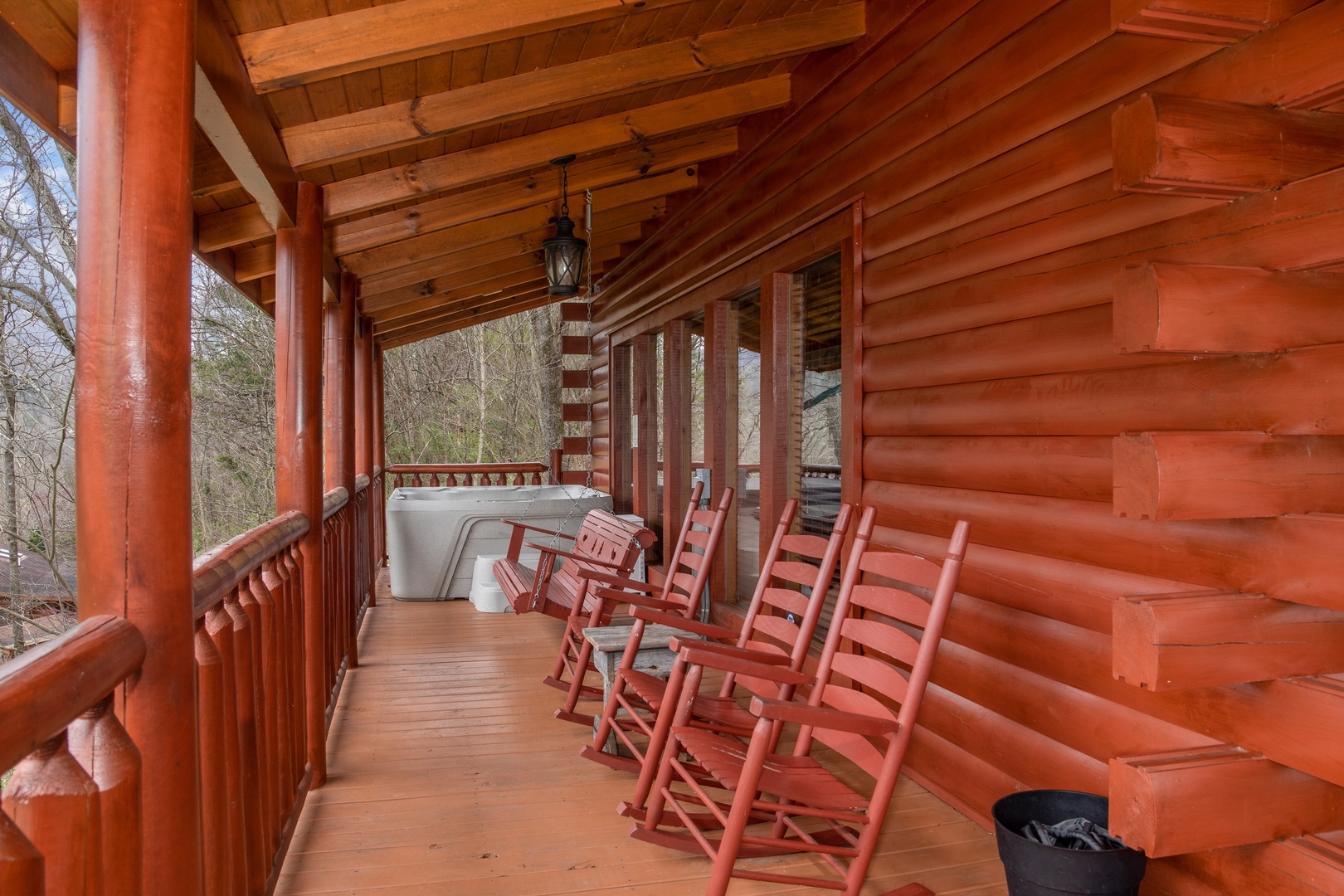 Rocking chairs and hot tub on a covered deck at Mountain View Meadows, a 3 bedroom cabin rental located in Pigeon Forge