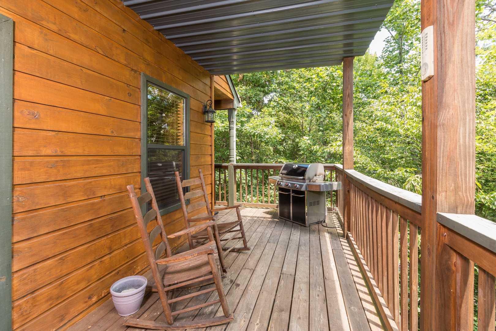 Rocking chairs and a grill on a covered deck at Stones Throw, a 4 bedroom cabin rental located in Pigeon Forge