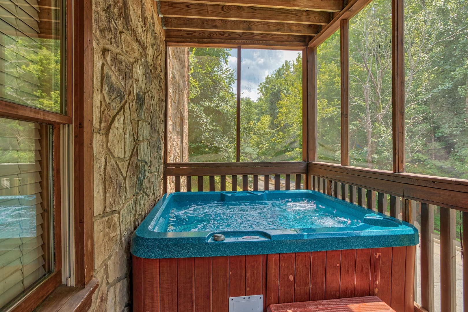 Hot tub on a screened and covered porch at Mountain Music, a 5 bedroom cabin rental located in Pigeon Forge