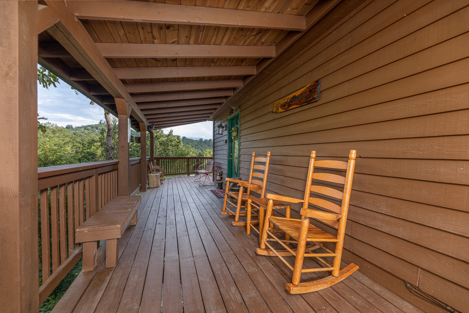 Rocking chairs and benches on a deck at Bearing Views, a 3 bedroom cabin rental located in Pigeon Forge