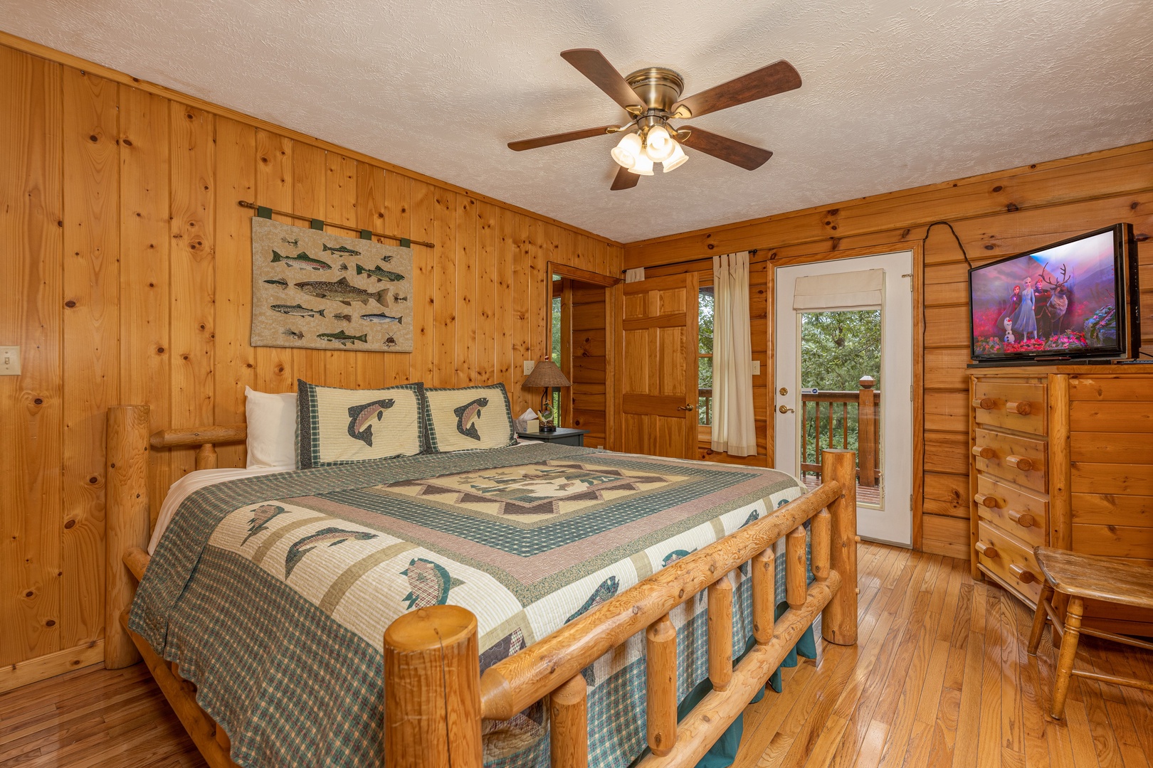 Bedroom with a king bed, dresser, TV, and deck access at Wildlife Retreat, a 3 bedroom cabin rental located in Pigeon Forge