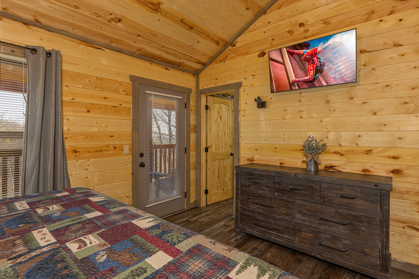 Dresser, TV, and deck access in a bedroom at Everly's Splash, a 4 bedroom cabin rental located in Pigeon Forge