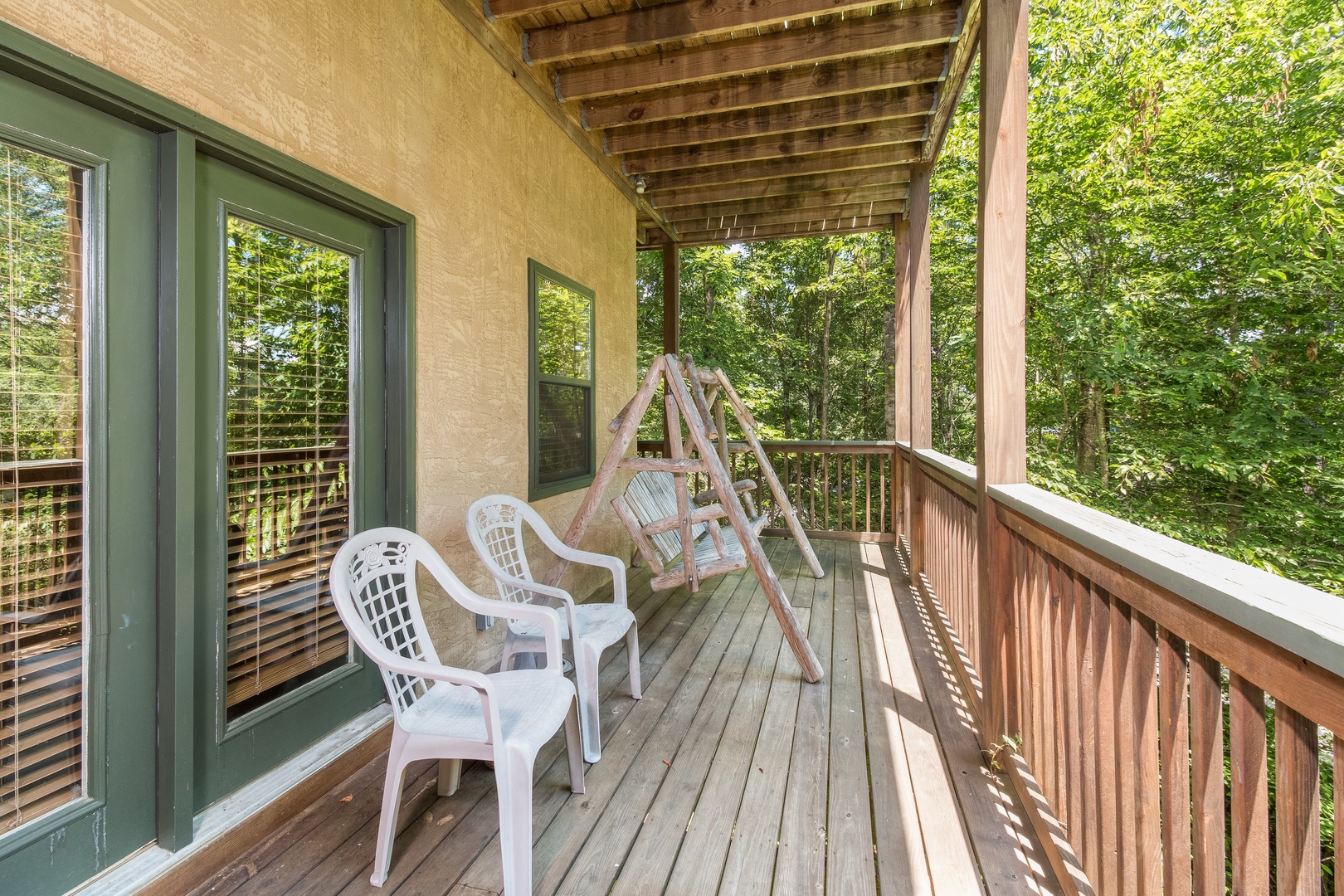Chairs and a swing on the deck at Stones Throw, a 4 bedroom cabin rental located in Pigeon Forge