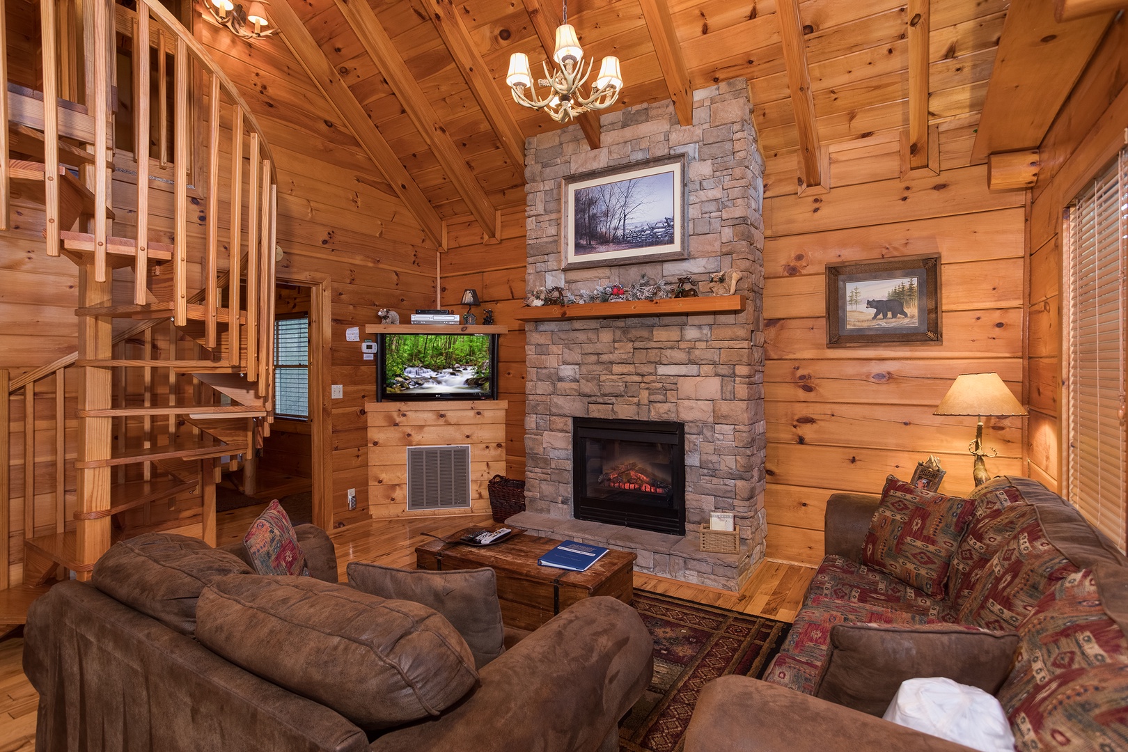 living room with a stone fireplace and spiral staircase at always & forever a 1 bedroom cabin rental located in pigeon forge