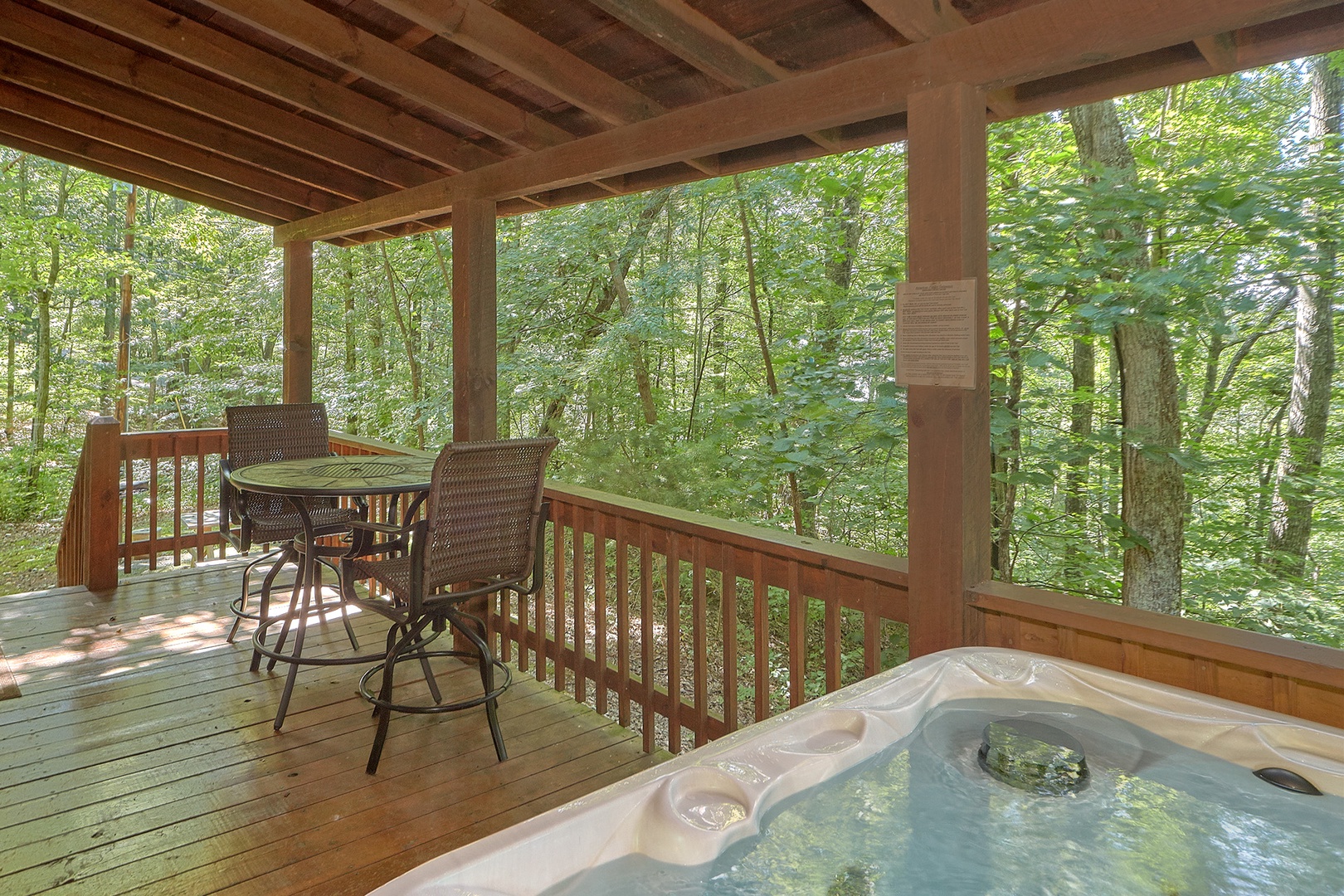 Hot tub on a covered deck with nearby seating at A Place to Remember, a 2 bedroom cabin rental located in Gatlinburg