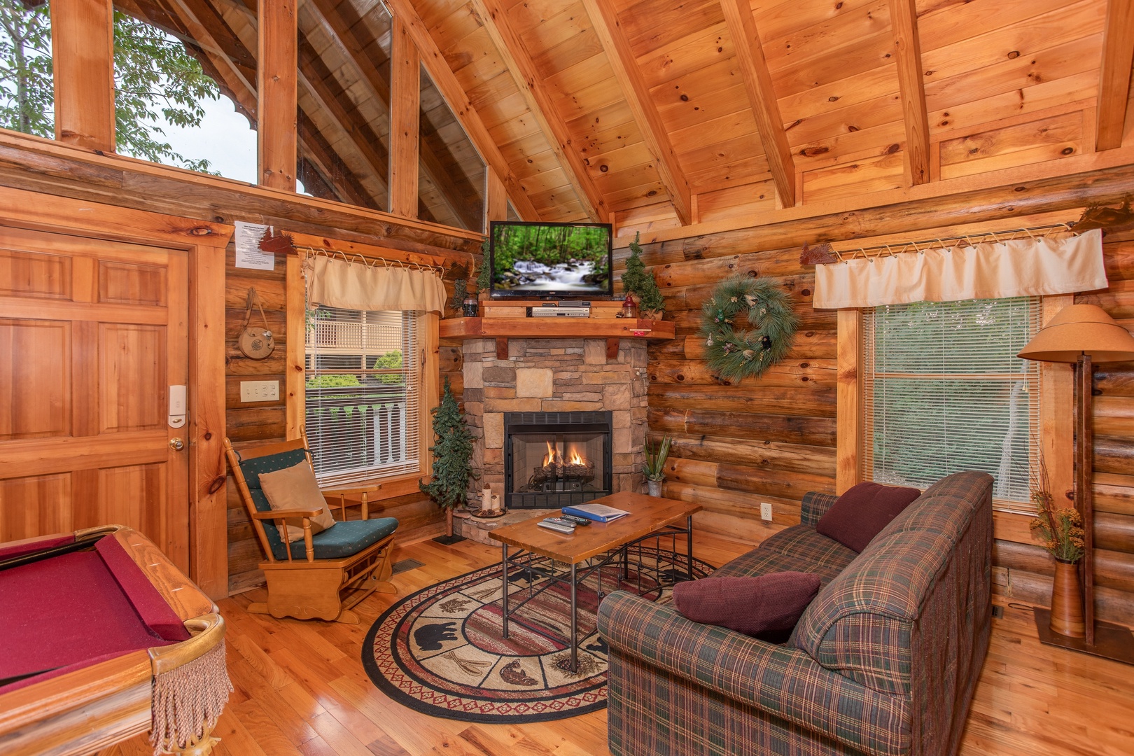 living room with a television and stone fireplace at alpine sunset thrill a 1 bedroom cabin rental located in pigeon forge