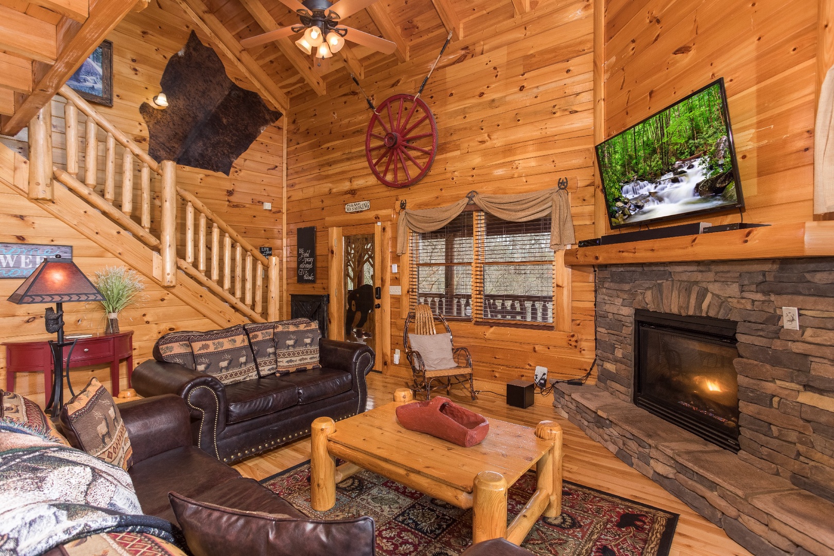 Living room with fireplace, TV, and front entry at Mountain View Meadows, a 3 bedroom cabin rental located in Pigeon Forge